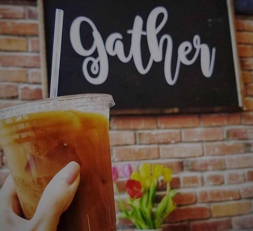 Cup of iced coffee in front of 'gather' sign at Alexa's Café in Bothell, Washington.