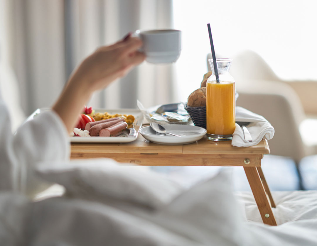 Person eating breakfast in bed at the Bothell Inn & Suites in Bothell, Washington.