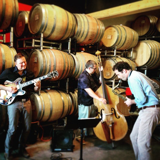 Band playing their instruments among the barrels of wine at Robert Ramsay Cellars.