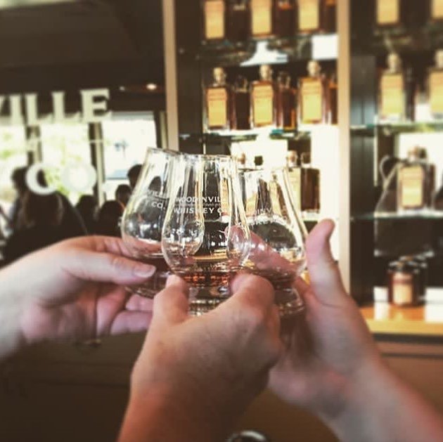 People cheersing tasting glasses of whiskey at Woodinville Whiskey Co near Bothell.