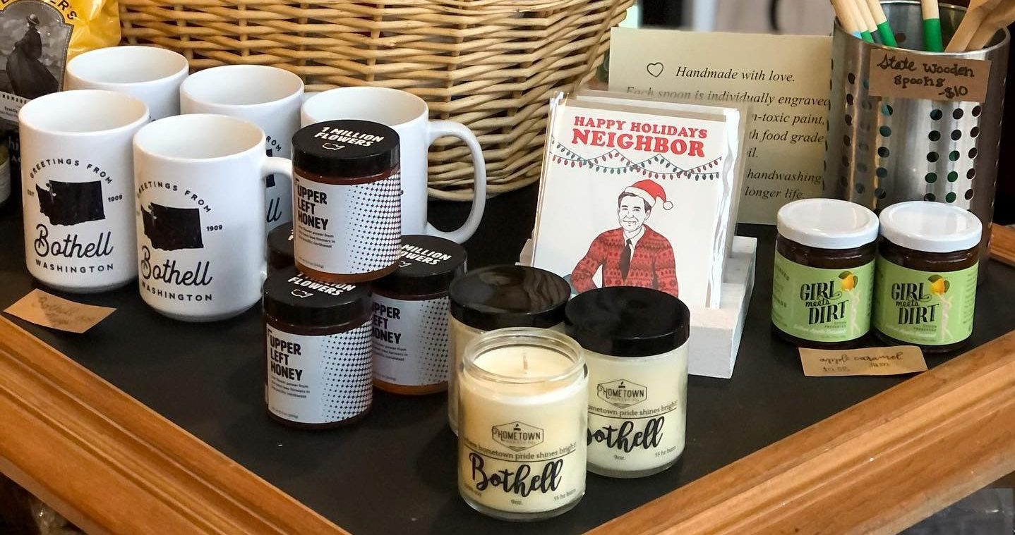 Bothell branded mugs and candles, cards, and other assorted gifts on a table.